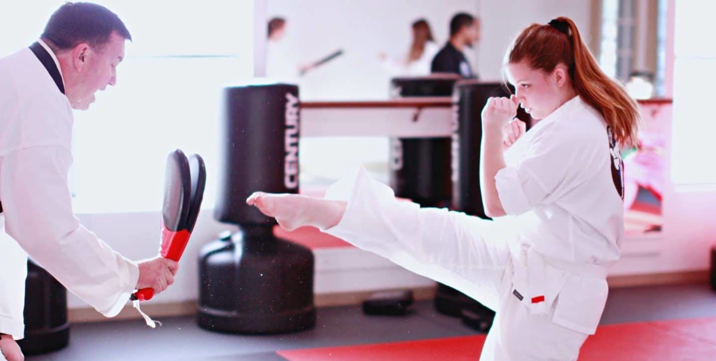 young taekwondo student kicking double sided training pad